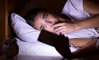 Obraz na płótnie Canvas Anxious Girl Using Cellphone Lying In Bed At Night