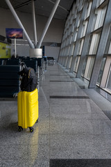 Travel yellow suitcase with black backpack at the empty airport