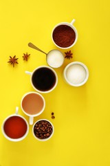 Flat lay composition of various cups of coffee, tea with sugar, cream and star anise on a bright yellow background. Coffee break. Top view.