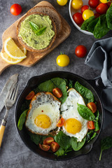Fried sunny eggs with spinach, avocado toast and fresh tomatoes. healthy breakfast food.