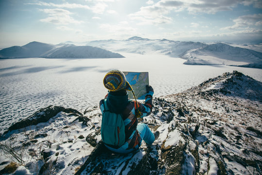 Sitting down and studying a map overlooking a frozen landscape.