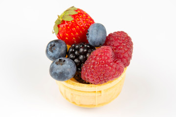 blueberries, raspberries, strawberries and blackberries in a waffle basket on a white background