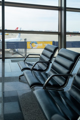 There are empty chairs, benches for passengers waiting for flights at the airport terminal, selected focus