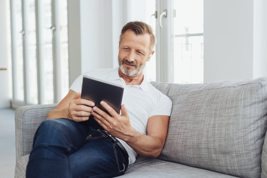 Middle-aged man relaxing on a sofa with a tablet