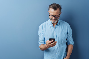 Man smiling as he reads a text message on a mobile