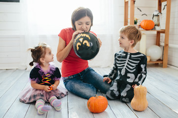 Fototapeta premium Happy family of mother and children prepare for Halloween in decorate the home