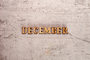The word December laid out in wooden letters on a light background. Close-up. Summer time years and months of the year.
