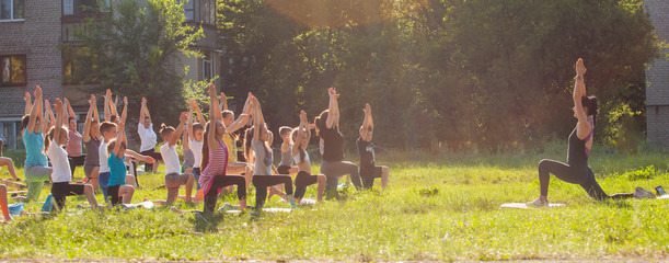 children do yoga with an outdoor trainer.
