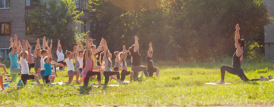children do yoga with an outdoor trainer.