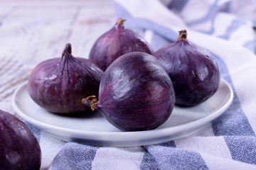 Ripe figs on ceramic plate on white wooden table