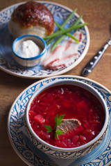 Soup borscht, garlic bun pampushka, sour cream and pork belly. Vertical image