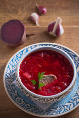 Soup borscht in blue bowl on wooden table. Vertical image