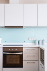 minimalist kitchen with white facades and blue glass apron with white table and chairs