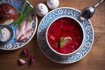 Soup borscht, garlic bun pampushka, sour cream and pork belly. Overhead, horizontal