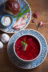 Soup borscht, garlic bun pampushka, sour cream and pork belly. Overhead, vertical