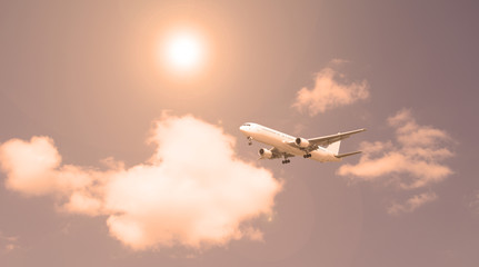 Passenger plane against the sky and white clouds. Evening sunset.