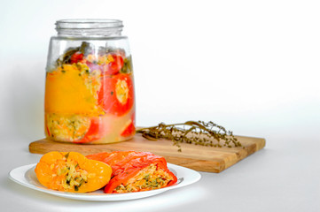 Sliced red and yellow whole peppers lie on a white plate close-up against an open can of peppers.
