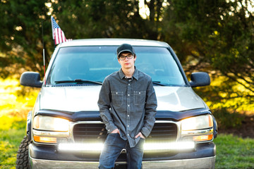 teenage boy from the south standing in front of his pickup truck with the LED car lights glowing. serious and thoughtful © Ursula Page