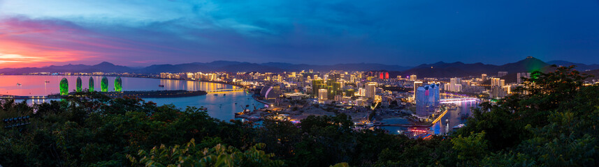 Night view of Phoenix island and Sanya city illuminated with city lights. View from Luhuitou Park on Hainan Island, China