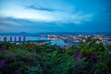 Night view of Phoenix island and Sanya city illuminated with city lights. View from Luhuitou Park on Hainan Island, China