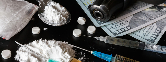 drug is a white powder, tablets, syringes sprinkled on a black table. Dangerous illegal business....