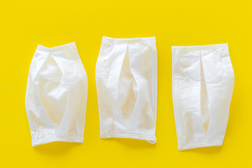 Flu prevention concept. Medical face mask on yellow background top view copy space