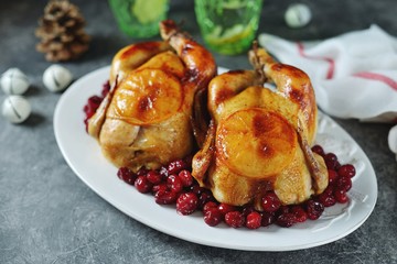 Two whole roasted chicken with cranberries and orange slices.