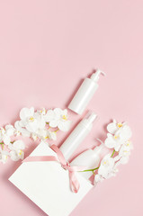 Obraz na płótnie Canvas Flat lay White cosmetic bottle containers gift bag White Phalaenopsis orchid flowers on pink background top view. Cosmetics SPA branding mock-up Natural organic beauty product concept Minimalism style