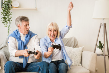 Senior couple having great time, playing video games