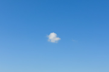 Bright blue sky with small white fluffy cloud