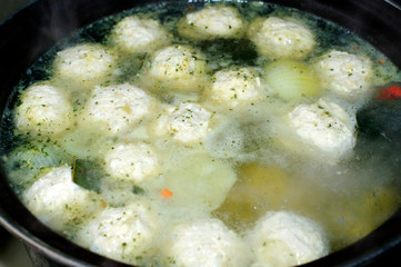 Close-up of a pan with soup and meatballs, cooking
