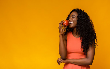 Happy african american woman enjoying red apple