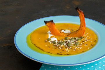 Vegetarian pumpkin cream soup on dark background.