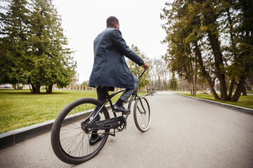 Businessman riding bicycle, going to work through autumn park
