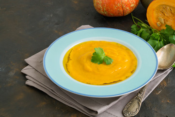 Vegetarian pumpkin cream soup on dark background.