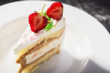 a piece of delicate cake, with slices of sliced strawberries, on a white plate on a white and gray background