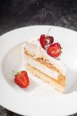 a piece of delicate cake, with slices of sliced strawberries, with the effect of powdered sugar, on a white plate on a white and gray background
