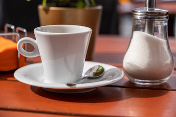cup of coffee and sugar bowl on a wooden table in a cafe.