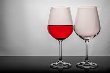 two glasses on a white background, one glass half full the second empty