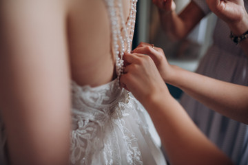 Obraz na płótnie Canvas a friend helps the bride to button the dress on the back
