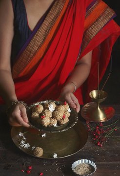 Person in red and blue saree dress holding grey metal bowl