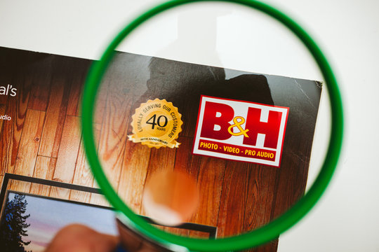 PARIS, FRANCE - 14 JAN 2018: B H photo Video pro Audio Magazine catalogue being read electronics and technology pov using loupe