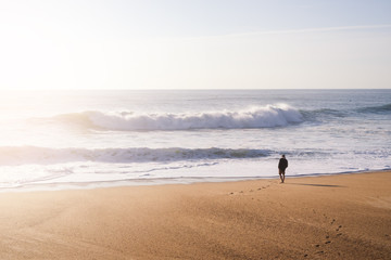 Man standing on the ocean shore in the sunset light