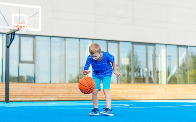 Obraz premium Adorable child playing the basketball in the basket field