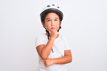 Beautiful kid boy wearing bike security helmet standing over isolated white background with hand on chin thinking about question, pensive expression. Smiling with thoughtful face. Doubt concept.