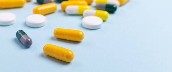 Multicolor tablets and pills capsules on blue background Heap of assorted various medicine tablets and pills Health care Close-up Horizontal banner Copy space