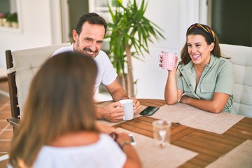 Fototapeta premium Beautiful family sitting on terrace drinking cup of coffee speaking and smiling