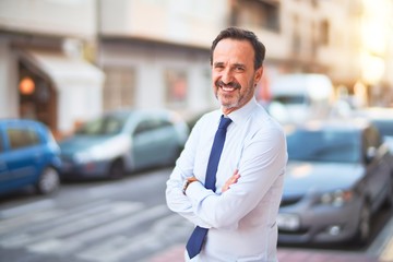 Middle age handsome businessman wearing shirt and tie standing on the street smiling