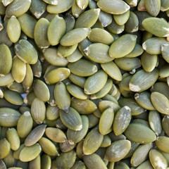 Green pumpkin seeds on wooden white background. Macro photo