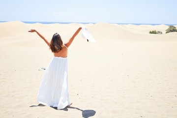 Fototapeta na wymiar Young beautiful woman sunbathing with open arms enjoying summer vacation at maspalomas dunes beach